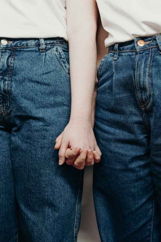 persons wearing denim jeans while holding hands